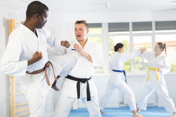 Active middle-aged man attendee of karate classes practicing fighting techniques during workout session