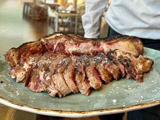 Medium-rare ribeye steak sliced and served on a green ceramic plate. 