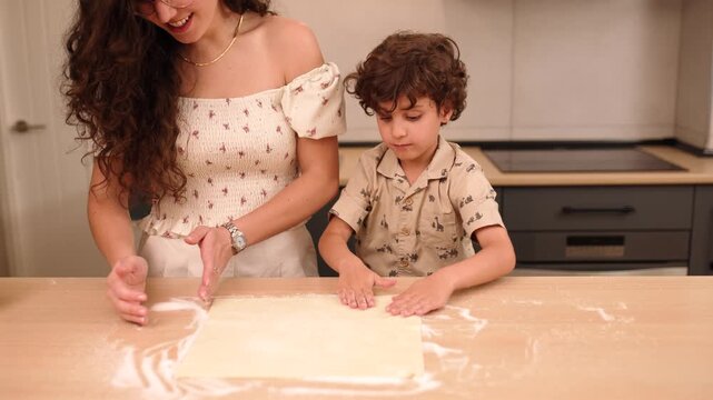 Mother and son preparing dough in kitchen