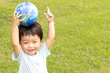 地球儀を持って草原で立っている男の子（2歳、日本人、笑顔）