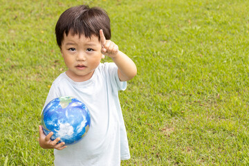 地球儀を持って草原で立っている男の子（2歳、日本人、笑顔）