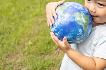 地球儀を持って草原で立っている男の子（2歳、日本人、笑顔）