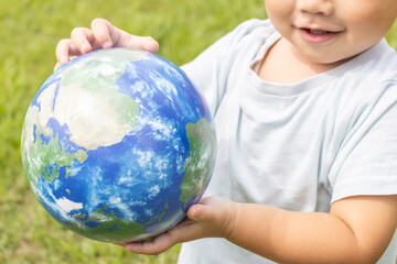 地球儀を持って草原で立っている男の子（2歳、日本人、笑顔）