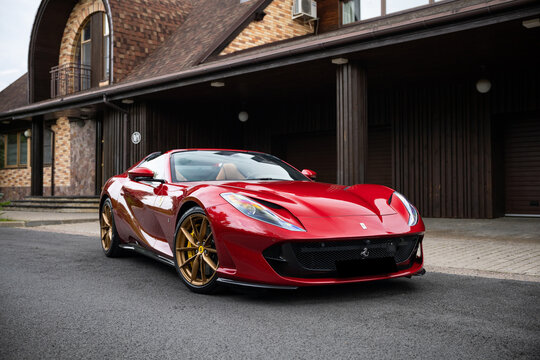 Ferrari 812 GTS: Striking red convertible supercar on a scenic drive through a green forest landscape logo detail 