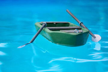 Wooden carved model of small punt with oars floating on level of pool
