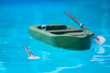 Wooden carved model of small punt with oars floating on level of pool