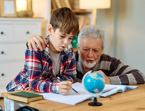 grandfather teaching grandson and helping him with homework at home - Powered by Adobe