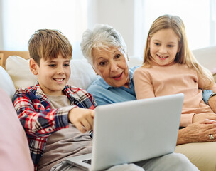 Family grandmother and grandchildren granddaughter and grandson, girl and boy, having fun using laptop at home