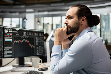 Investment consultant frowning while looking at candlestick charts, bummed by poor portfolio...