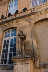 Obraz premium Ancient Statue of Man in front of Window Arles France 