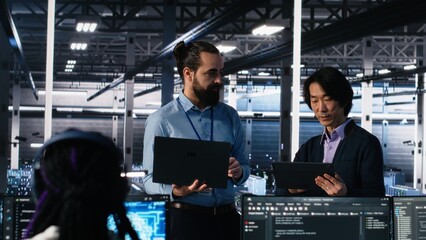 Data center manager supervising work done by programmers working on neural network software. Server...