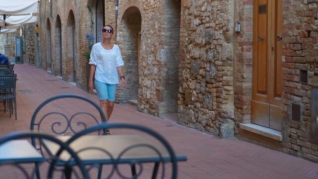 Tourist walking in monticchiello alley in tuscany. Tourist woman walking through narrow, characteristic stone alley in medieval tuscan village of monticchiello, in siena province, italy
