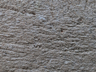 Close-up of rough grey sand and cement or concrete mix texture for exterior wall coating, plastering, construction and masonry background. Weathered coarse grainy surface with holes, irregular relief.