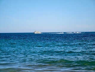 Obraz premium vast sea scene, extensive maritime landscape with faroff vessel and tranquil waves rolling in