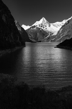 Breathtaking view of  Paron lake, a stunning turquoise glacial lake in Peru's Cordillera Blanca, near Caraz. Steep cliffs frame the water, leading to snow-capped peaks under a clear blue sky.