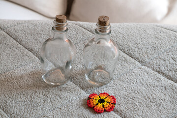Two small glass bottles with corks and a beaded flower decoration