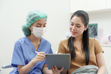 Dental assistant wearing surgical cap and mask reviewing dental information on tablet. Preparation...