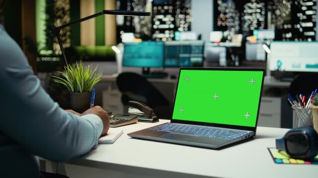African american man working with green screen on laptop in corporate workspace, checking online data and insights in strategy room. Male general manager setting the business agenda. Camera A.