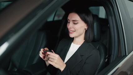 Smiling woman in black blazer holding car key inside vehicle, showcasing excitement of new car purchase, representing the joy of buying a car