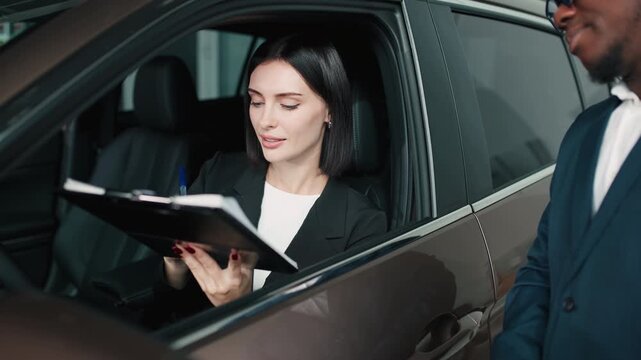 African American man in a suit is handing over keys to a smiling woman in a car dealership, showcasing the excitement of buying a new vehicle with modern design elements