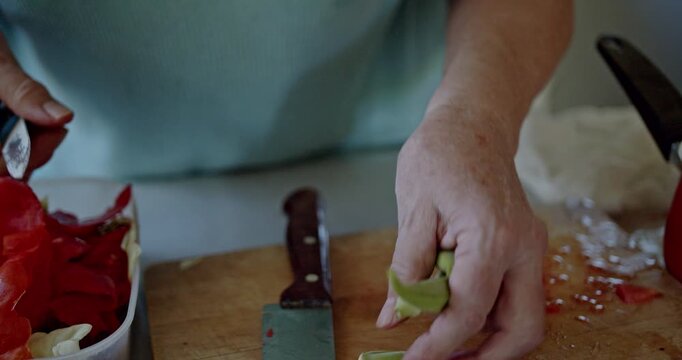 Witness the meticulous process of hands preparing fresh okra pods on a wooden cutting board.