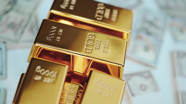 Stacked fine gold bars resting on a bed of american dollar bills, representing immense wealth, financial investment, and the value of precious metal reserves in a stable economy