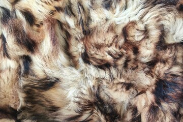 Close-up texture of soft brown and beige animal fur with natural stripes and patterns. Realistic detailed background for textile design, fashion fabric, or wildlife concept.