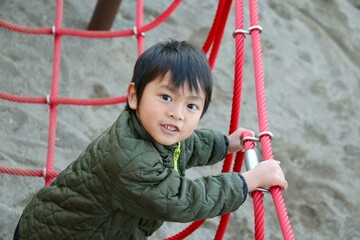 休日に公園の遊具で遊ぶ男の子　アジアの日本人の子供　楽しい笑顔