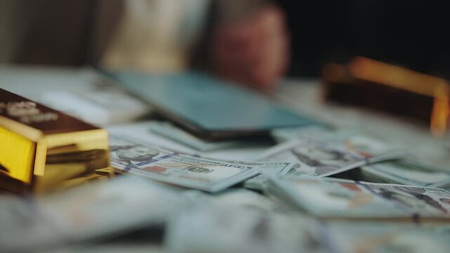 Unrecognizable criminals sitting around a table covered with stacks of dollar bills and gold bars, counting their illicit gains from illegal activities in a clandestine meeting