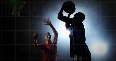 Jumping dark jersey player shooting basketball at hoop under stadium light on gym court, copy space