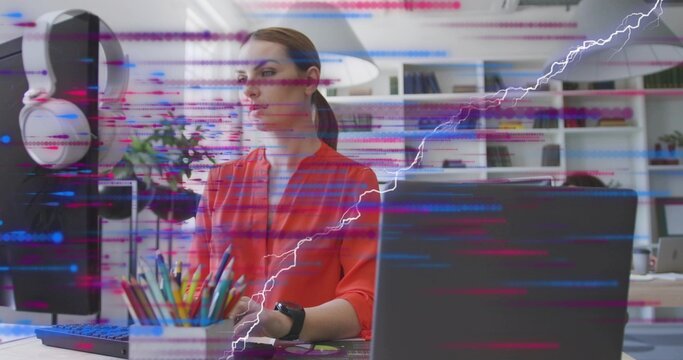 Typing woman wearing red blouse at white desk with monitor and laptop showing code overlay