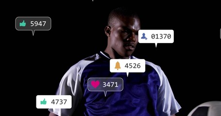 Soccer player holding soccer ball wearing jersey in studio, social media notification icons