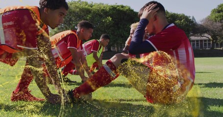 Stretching male soccer teammates wearing red jerseys, cleats on park pitch, with neon orange vests
