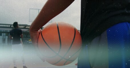 Player in sportswear holding basketball on rooftop court, with hoop and transparent backboard