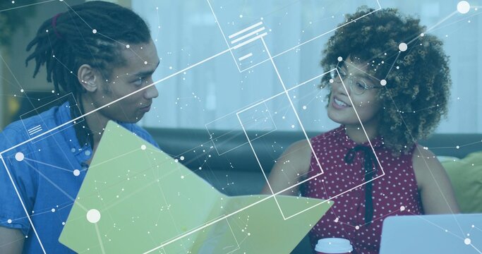 Two professionals reviewing green chart on sofa in lounge, with laptop, coffee cup and data overlay