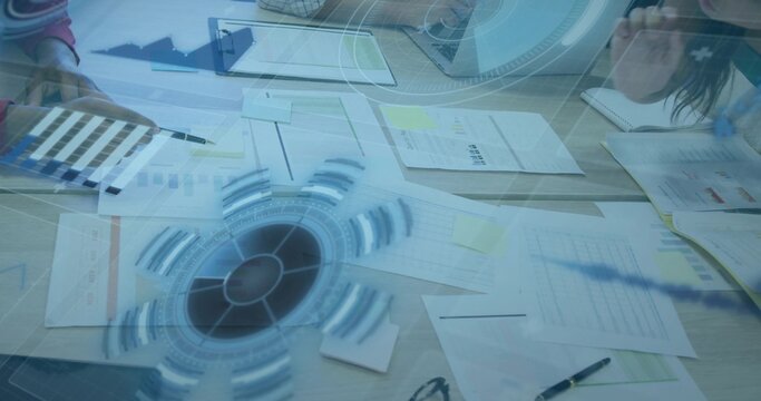 Colleagues analyzing charts and holographic overlay at conference table with sticky notes