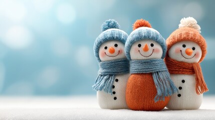 Obraz premium Three cute knitted snowman toys in winter hats and scarves. Happy Christmas holiday decoration on a snowy background. Winter scene with copy space