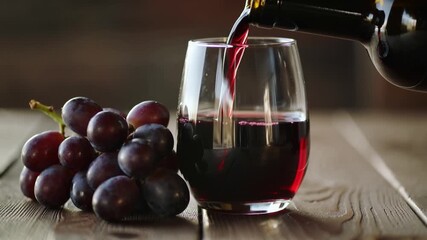 Vinous Indulgence: A pour of rich red wine streams into a clear glass, accompanied by a cluster of fresh grapes, evoking the sensory experience of a fine vintage. 