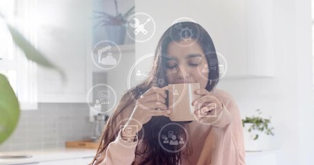 Woman lifting mug and sipping slowly, generating tech icons around upper body boosting productivity - Powered by Adobe