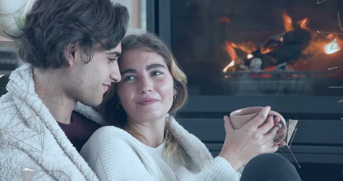 Home decor showing couple settling on sofa by fireplace wrapping in blanket and inhaling mug warmth
