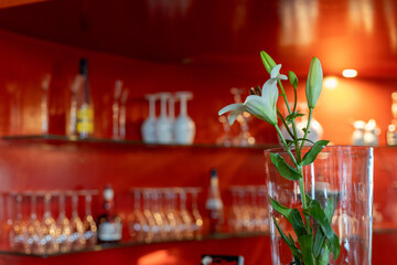 Elegant flower arrangement in a warm, modern bar setting with glassware in the background