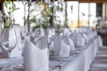 Elegant dining setup in a bright restaurant with large windows showcasing greenery