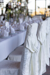 Elegant dining setup featuring white chairs and a long table decorated for a special event in a bright venue