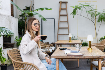 Young woman enjoying coffee while working on laptop at an outdoor cafe