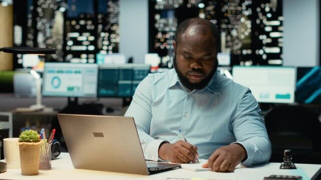 African american strategist ripping a paper after writing the wrong idea, restarting work in rage and crumpling the page sheet. Discontent man does a typo mistake while transcribing. Camera B.