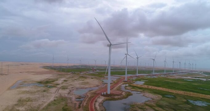 Dunas e lagoas dos Pequenos Len&ccedil;&oacute;is Maranhenses com turbinas e&oacute;licas girando capturadas por drone em Paulino Neves, Maranh&atilde;o