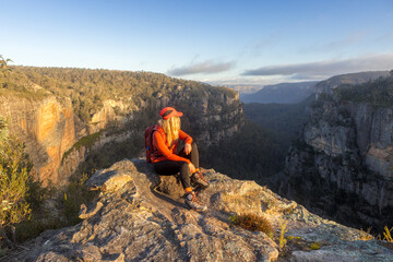Hiker resting on a rock overlooking a canyon with sandstone cliff walls