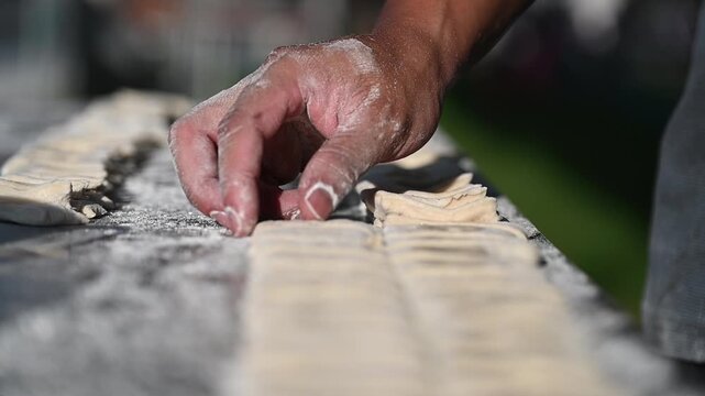 Closeup of fresh dough, Hand shaping dough with flour dust table sunlight, slow motion video shows craft detail and texture gentle grip, calm focus, artisan feel outdoors dusted dough strips metal 