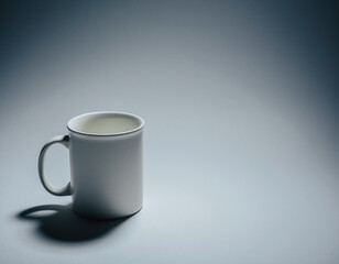 A single matte-white ceramic mug with a fine lip and soft shadow, positioned lower-left on a seamless pale gray backdrop; 70% negative space to the right for typography. Soft top-down key light, gentl