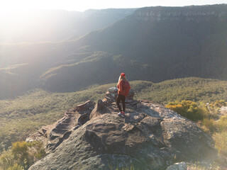 Woman on rock with abacklit  sun filled valley